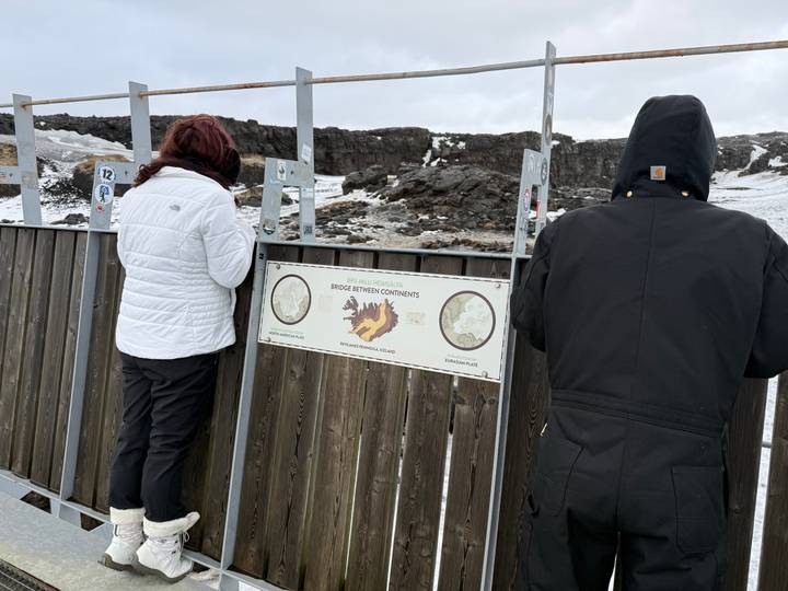 Travellers read an information board at the Bridge Between Continents on a bleak, snowy landscape.