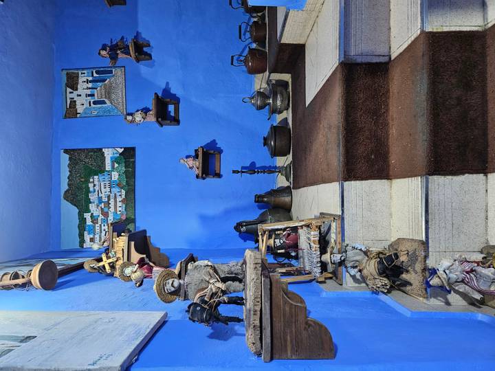 Blue-painted stairwell displaying Moroccan figurines, pottery and craft items.