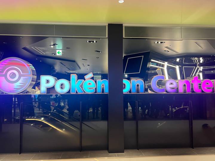 Bright neon sign reading “Pokémon Center” inside a modern retail space.