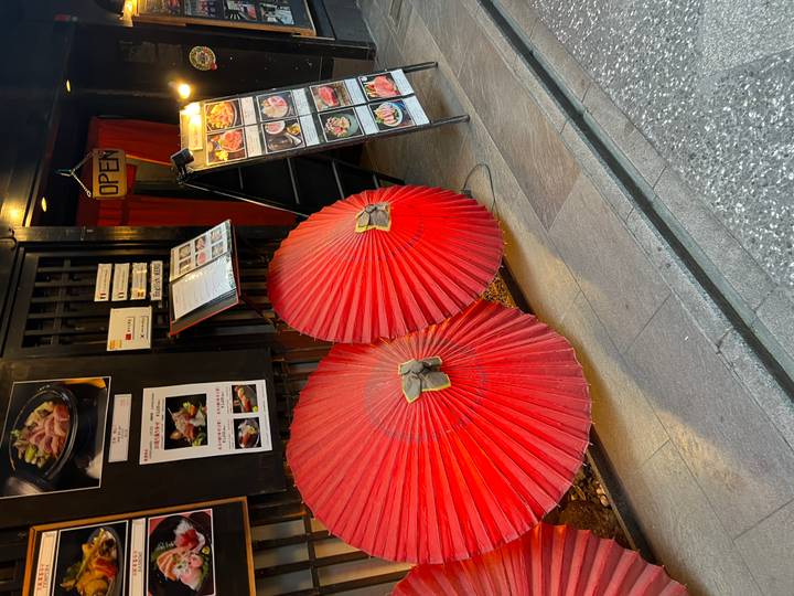 Two large red paper umbrellas leaning outside a traditional Japanese restaurant entrance.