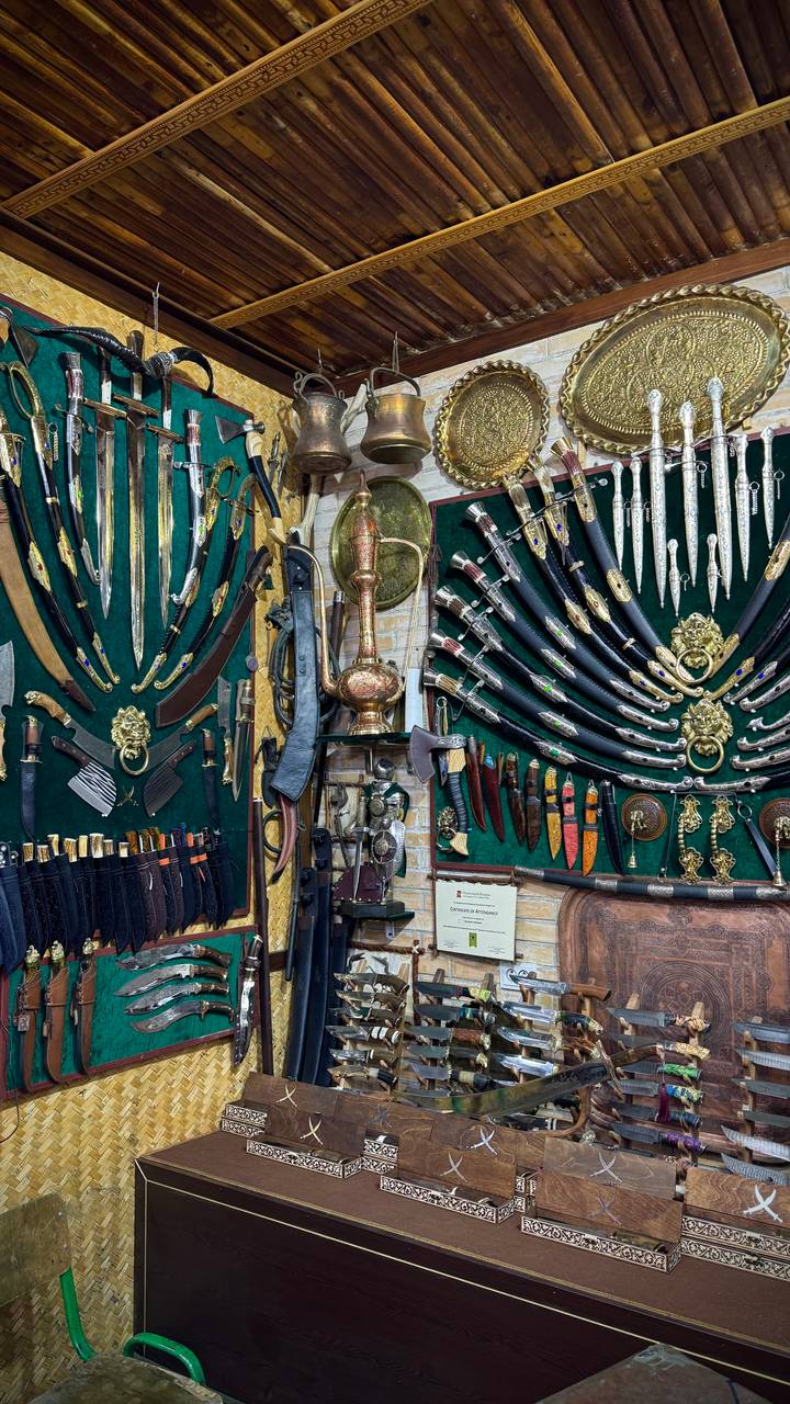 A richly decorated display of ornate daggers, swords, and antique weapons lines a museum wall.