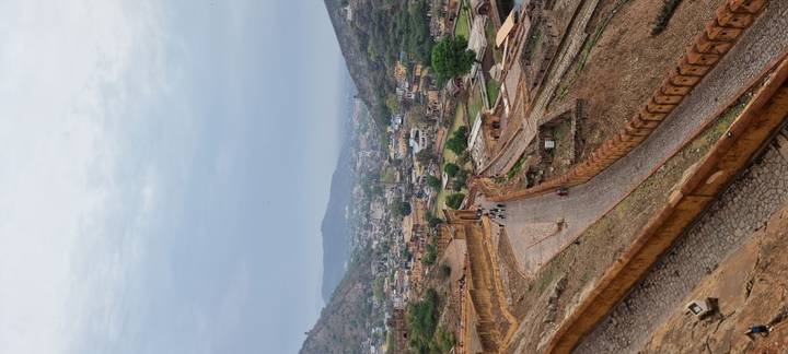 Sweeping hilltop view over ancient ramparts and winding pathways leading to a town nestled in a valley