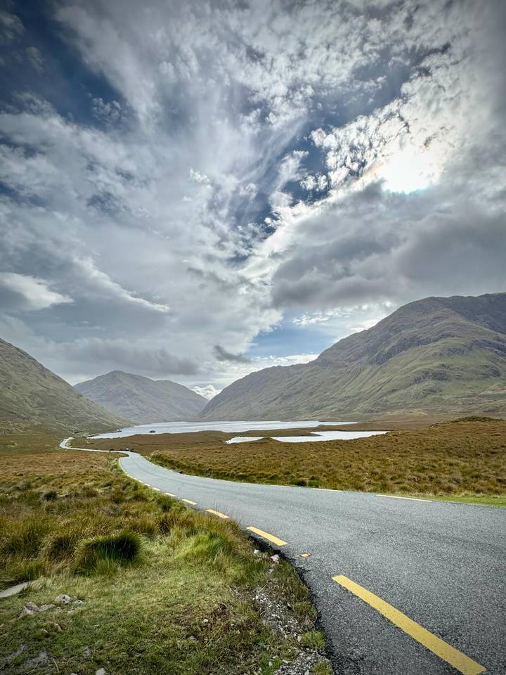 Serene mountain lake nestled between misty green peaks under a dramatic cloudy sky