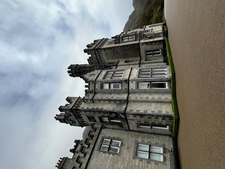 Grey stone castle-like mansion with crenellations set against a misty Irish sky