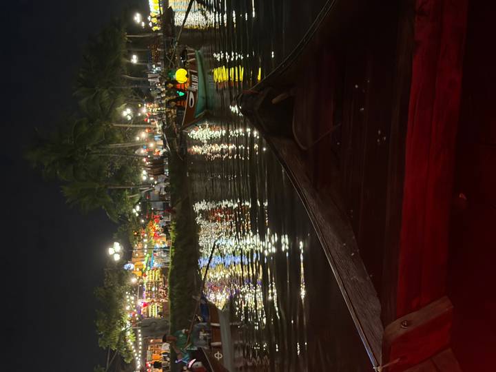 Nighttime view from a wooden boat of Hoi An’s colorful lantern-lit waterfront reflected in the river