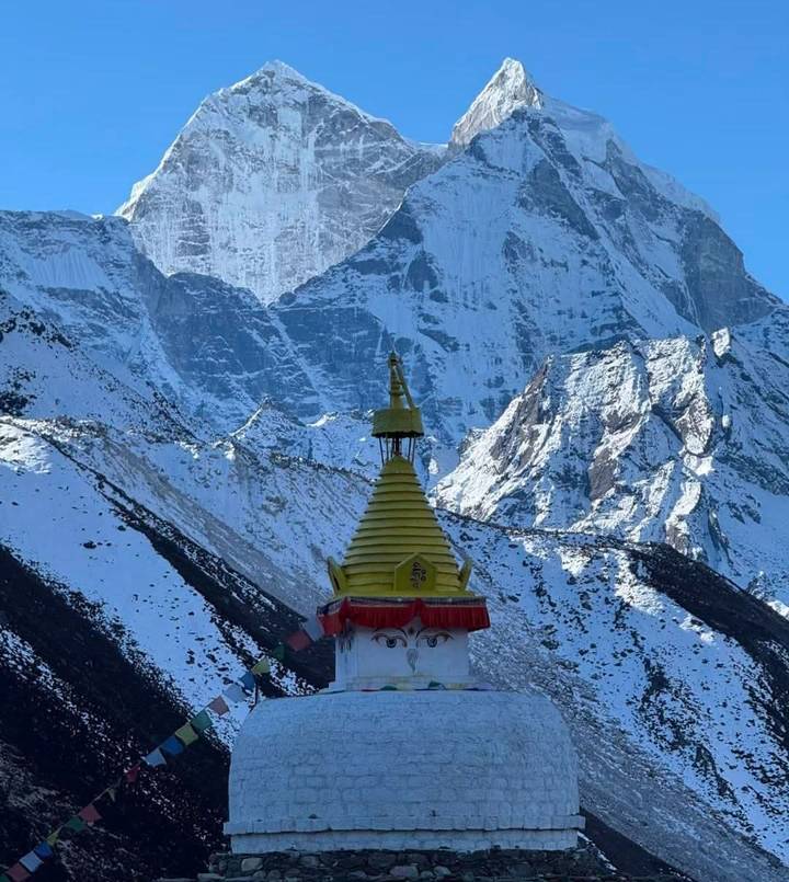 Bright stupa topped with Buddha eyes set against towering Everest region peaks blanketed in snow
