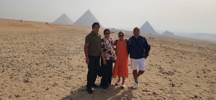 Family posing on the desert plain with the iconic Pyramids of Giza rising behind them.