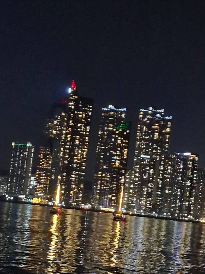 Tilted night shot of high-rise buildings with colorful lights against a dark sky.