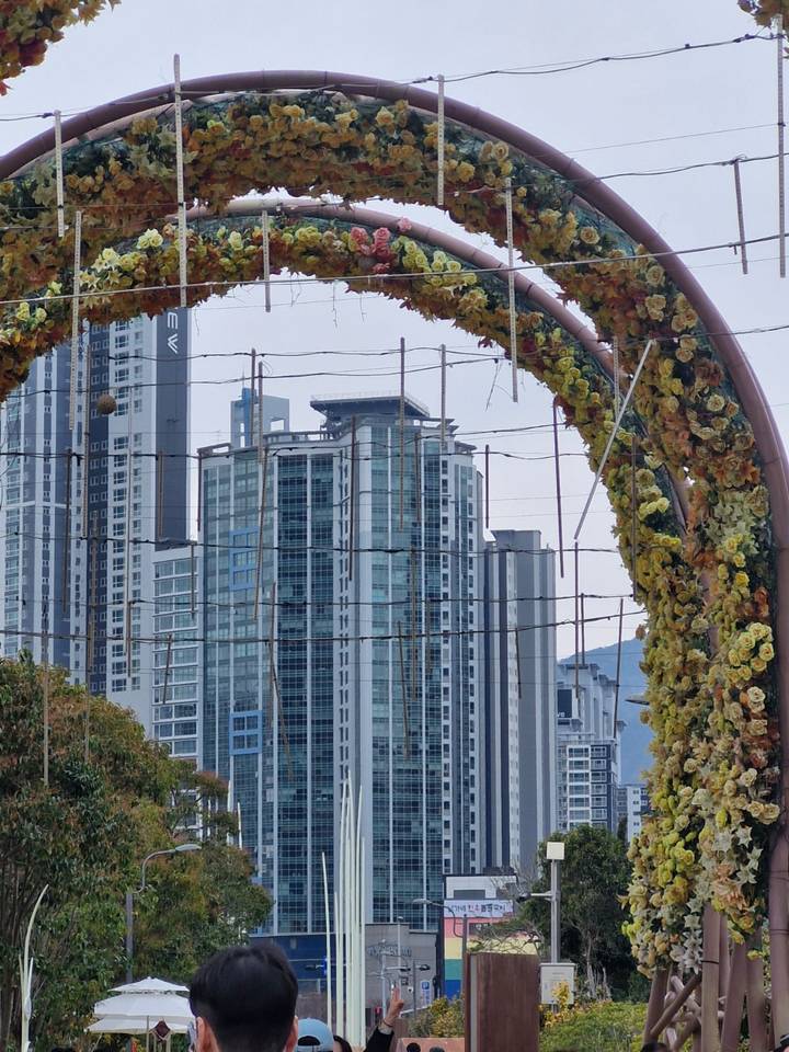 Modern urban skyline framed by a decorative floral archway structure in the foreground.