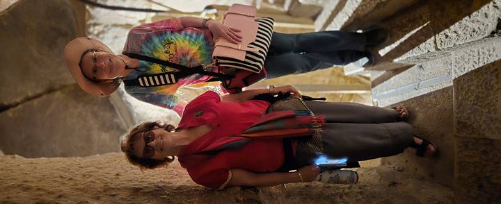 Two women pose on stone steps inside an ancient Egyptian tomb.