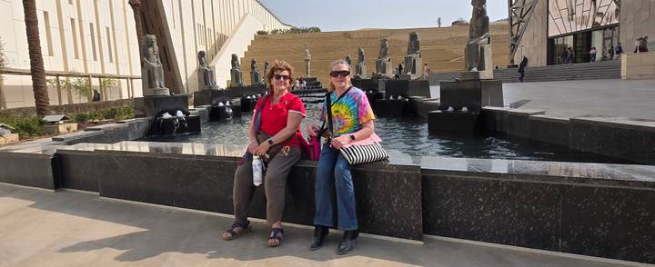 Two visitors sit by modern fountains outside Egypt’s new museum complex.