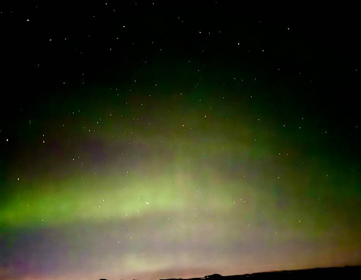 Green aurora borealis shimmering across a star-filled night sky