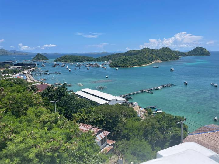 Panoramic view over Labuan Bajo harbour dotted with boats and green islands