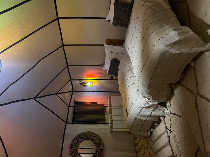 Cozy twin beds inside a canvas desert tent softly lit by a colorful lantern.