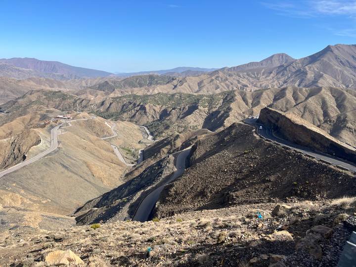 A sweeping view of rugged Atlas mountain ridges and winding roads fading into the distance.
