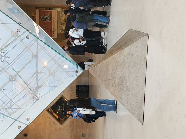 Visitors gather around the inverted glass pyramid inside the Louvre Museum's lower lobby.