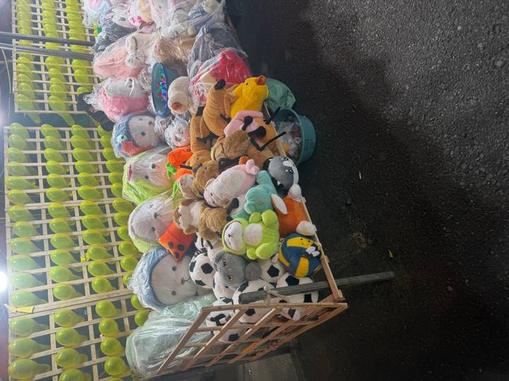 Night market stall displaying plush toys and carnival prizes under bright lights.