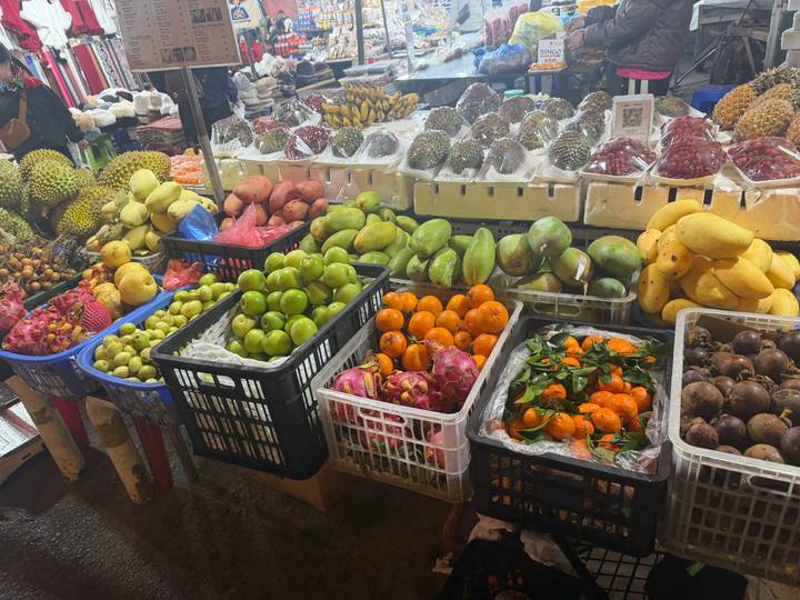 Abundant tropical fruits arranged in colorful baskets at an indoor market.