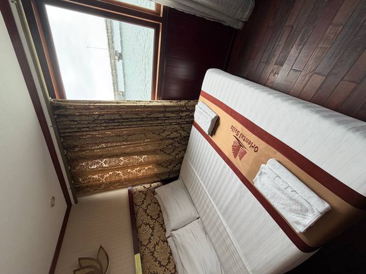 Cozy cabin room with double bed, embroidered runner and window view of harbour.