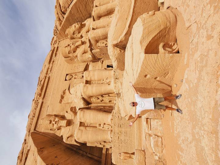 Visitor spreads arms joyfully before the colossal statues of Abu Simbel temple