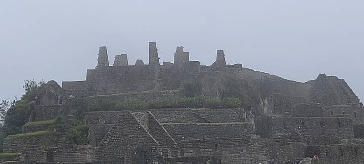 Zoomed-in fog-covered stone structures on the upper section of Machu Picchu.