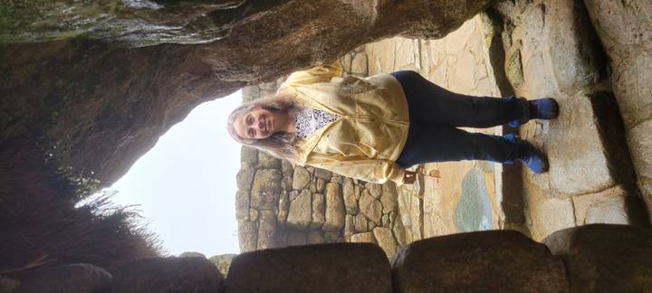 Smiling woman posing in a stone doorway of the Inca ruins, wearing casual travel clothes