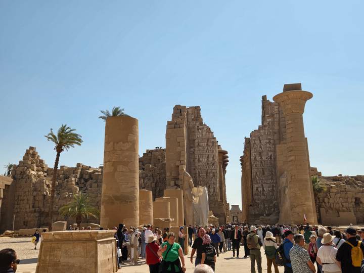 Wide daytime view of the massive sandstone columns and ruined pylons of Karnak Temple with crowds at the base