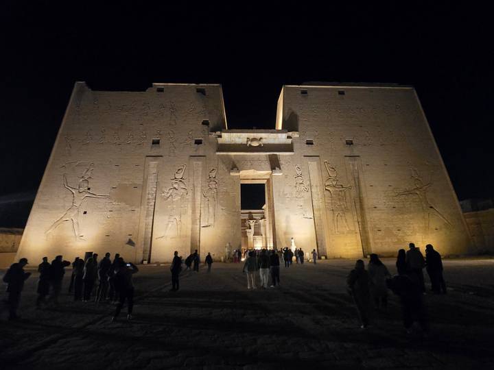 Night-time illumination of the Temple of Horus at Edfu with visitors silhouetted in front of the monumental façade