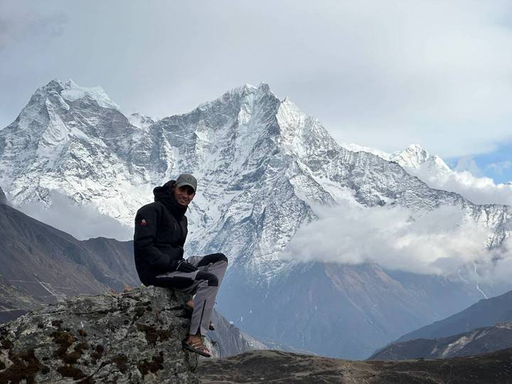 Traveller sitting on a rock overlooking dramatic snow-covered Himalayan peaks.
