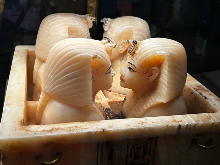 Close-up of intricately carved alabaster canopic jar heads displayed in an Egyptian museum.
