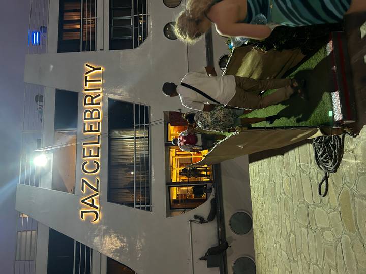 Travellers walk a gangway to board the lit-up Jaz Celebrity Nile cruise ship at dusk.