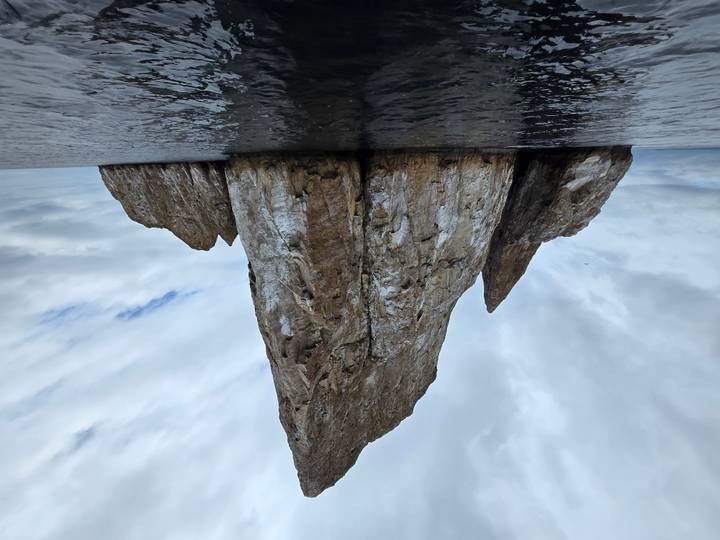 Sheer vertical rock island known as Kicker Rock rises dramatically from the Pacific Ocean under a moody sky.