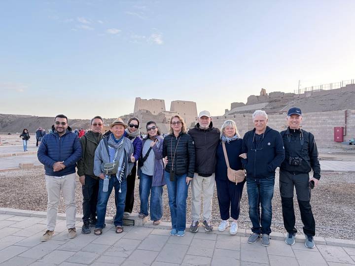 Tour group poses in front of ancient sandstone temple ruins at Egypt's Edfu
