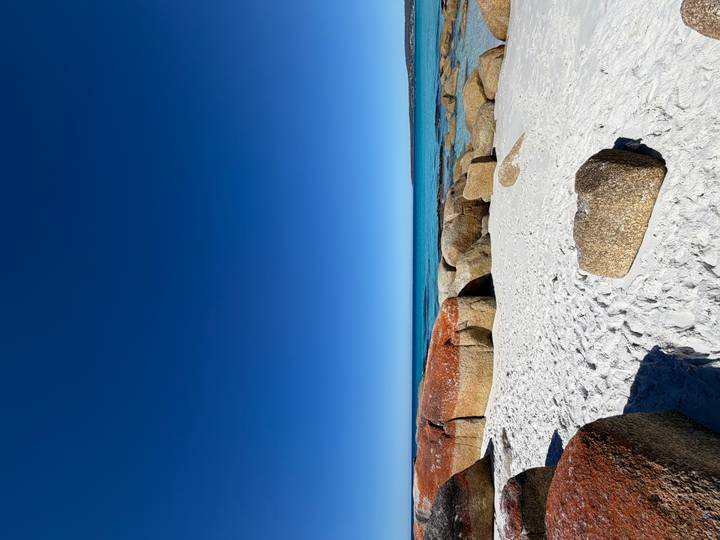 Pristine white sand and orange-hued boulders meet vivid blue sea at Bay of Fires