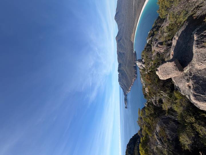 Panoramic view over Tasmania's curved Wineglass Bay and forested peninsula from lookout