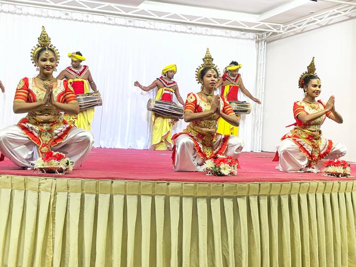 Traditional Sri Lankan dancers perform on red-carpeted stage with drummers in background