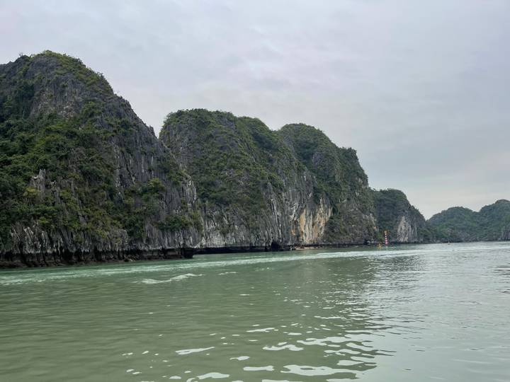 Limestone karst islands rising from calm green waters under an overcast sky