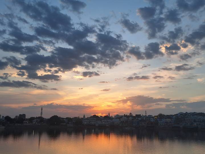 Colorful sunset over an Indian town skyline with dramatic clouds lit by orange glow