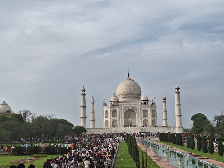 Frontal classic view of Taj Mahal with reflecting pool and crowds on marble terrace