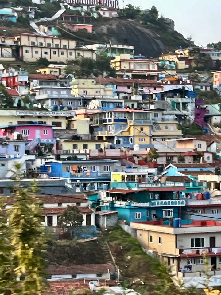 Cluster of brightly painted hillside houses and rooftops create a colourful patchwork in a mountain town.