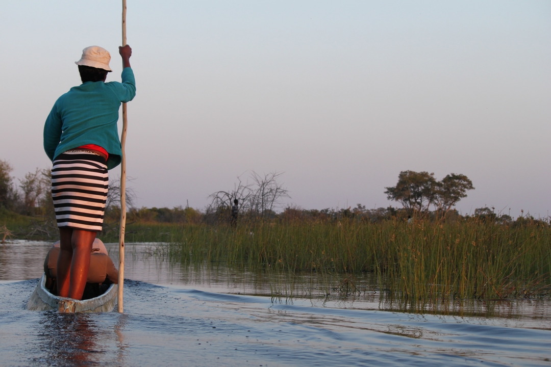Two people on a canoe in a wetland during sunset.