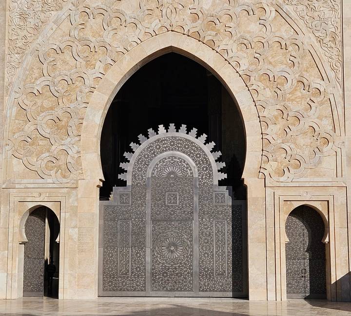 Detail of ornate arch and carved stonework at Hassan II Mosque entrance.
