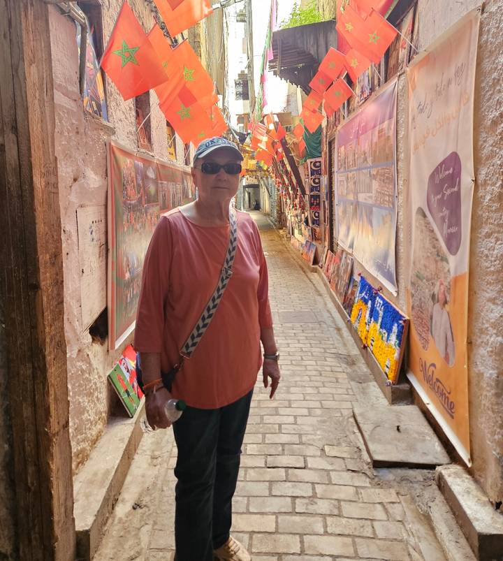 Traveler stands in narrow souk alley lined with colorful art and textiles.