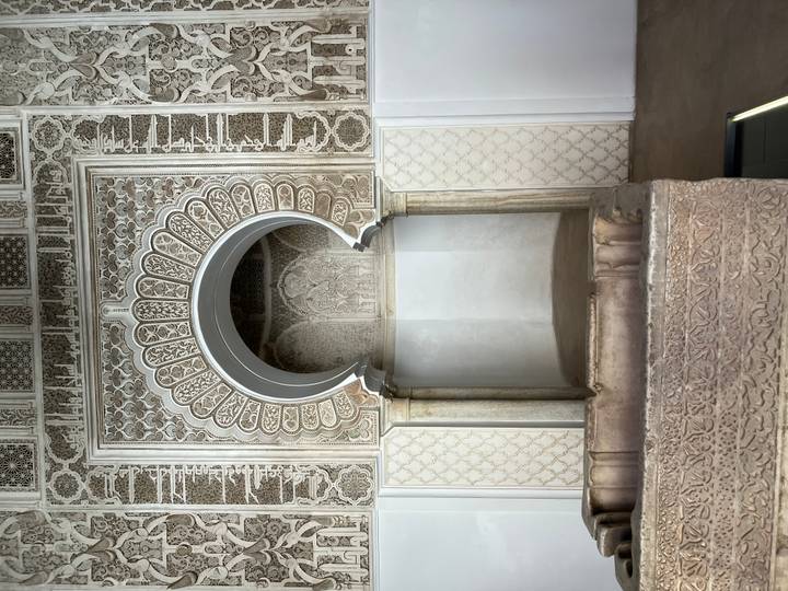 Detailed carved stone arch and columns of an ornate Moroccan interior.