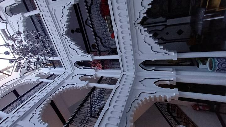 Ornate multi-storey riad courtyard with carved arches, wrought-iron balconies and central chandelier.