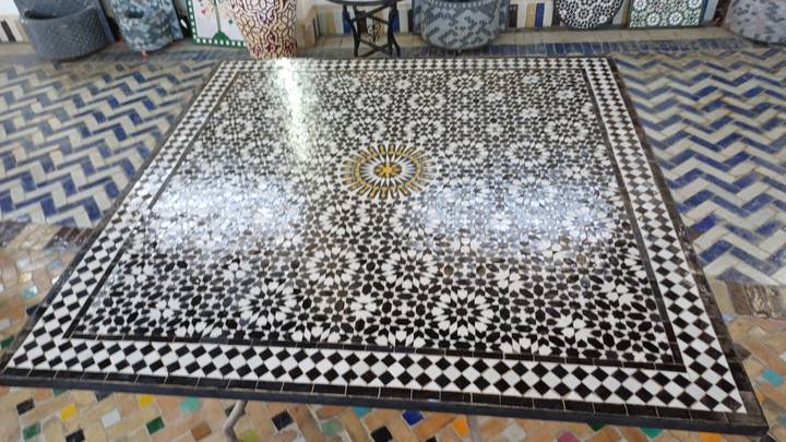 Intricate square mosaic tile panel displayed on a workshop floor with geometric patterns.