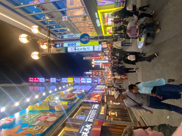 Crowded neon-lit street lined with tall signboards and shops at night