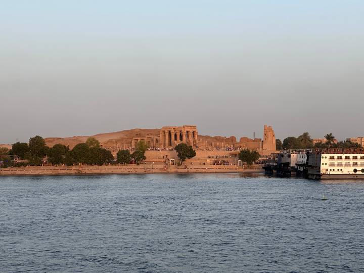 Ancient riverside temple ruins glowing in warm evening light across the Nile