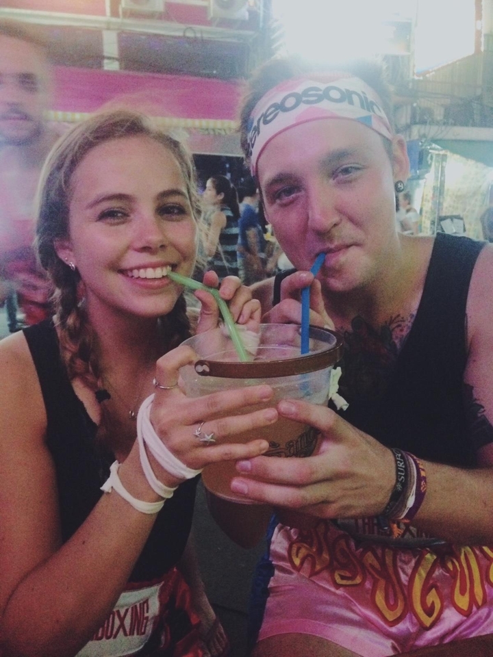 Two people sharing a drink from a bucket with straws.