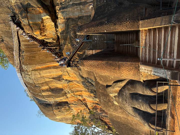 Visitors climbing steep metal stairs up the dramatic rock face of Sigiriya